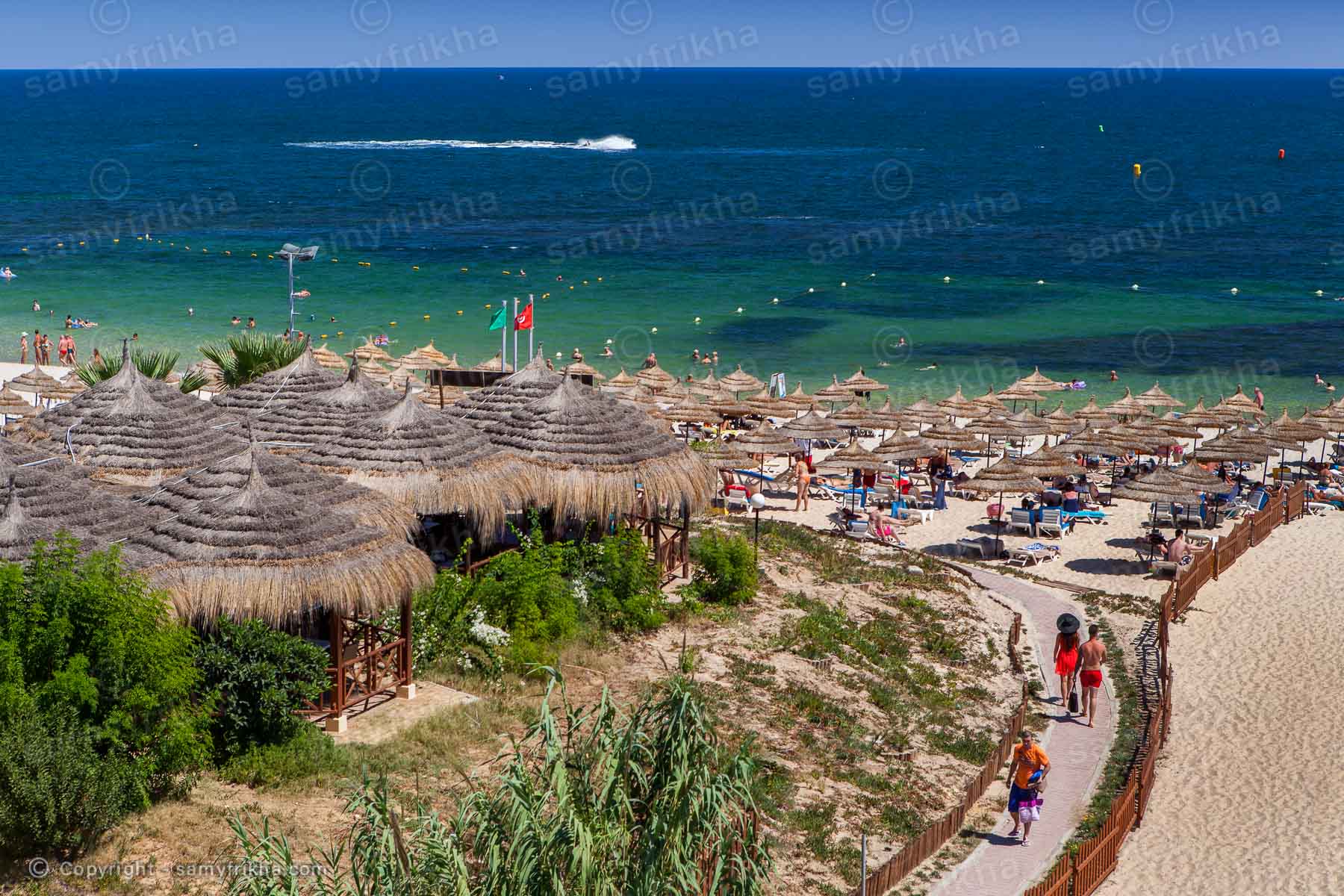 Plage privée d'un hôtel avec parasols et espace balnéaire.
