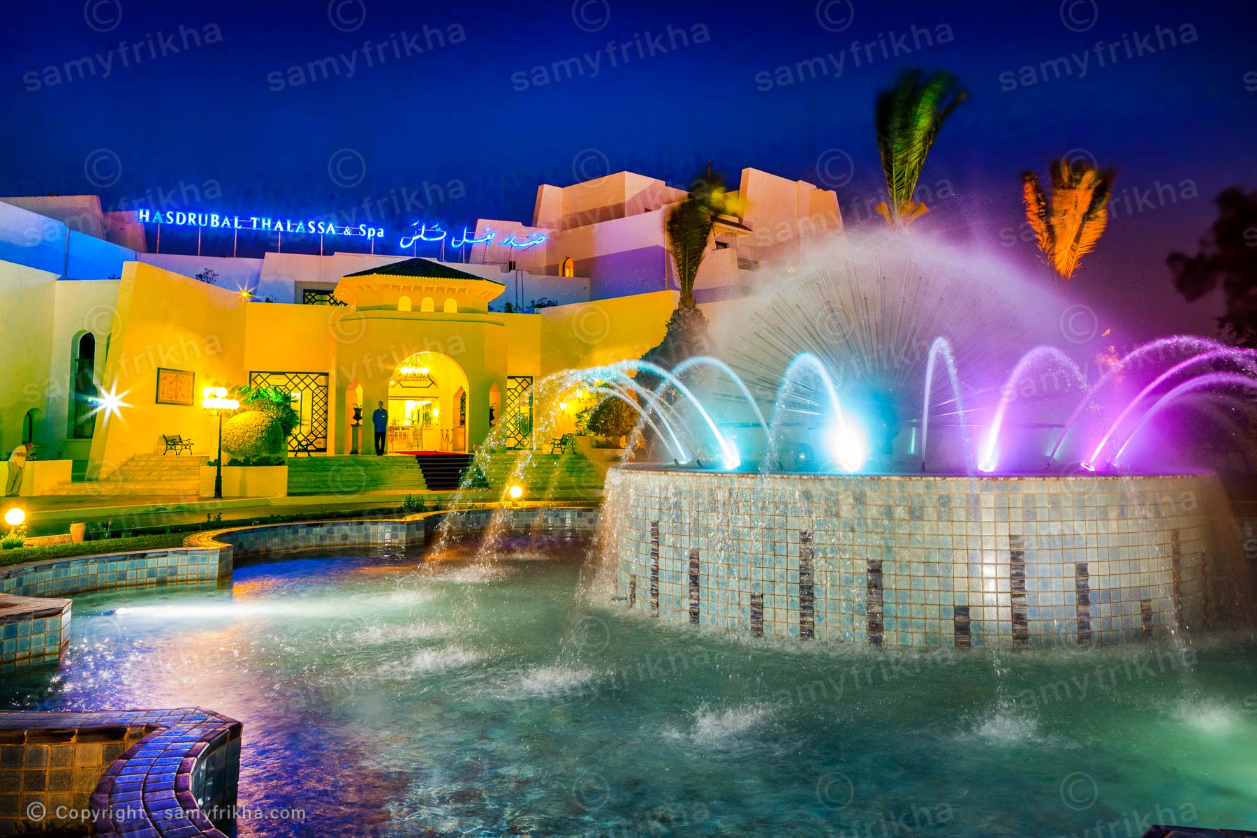Piscine d’hôtel avec fontaines et éclairage nocturne